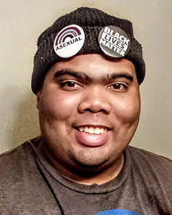 Headshot of Marshall, a Black man wearing a beanie with "Asexual" and "Black Lives Matter" pins on it.